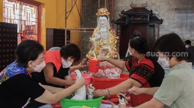 Petugas membersihkan patung dewa di Vihara Amurva Bhumi, Jakarta, Selasa (25/1/2022). [Suara.com/Septian]