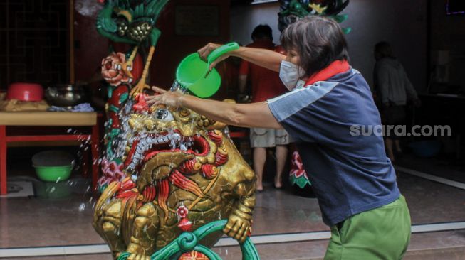 Petugas membersihkan patung di Vihara Amurva Bhumi, Jakarta, Selasa (25/1/2022). [Suara.com/Septian]