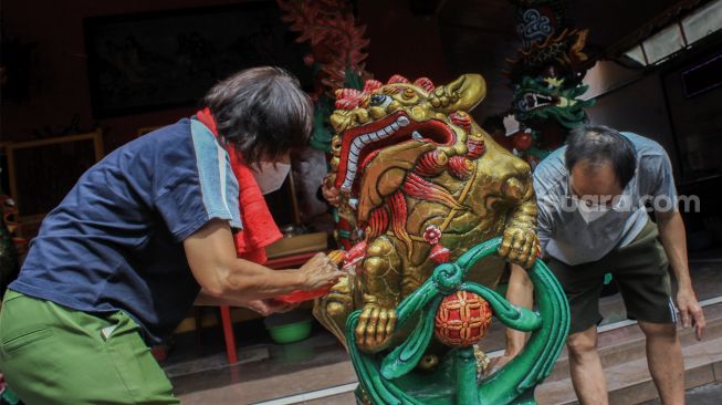 Petugas membersihkan patung di Vihara Amurva Bhumi, Jakarta, Selasa (25/1/2022). [Suara.com/Septian]