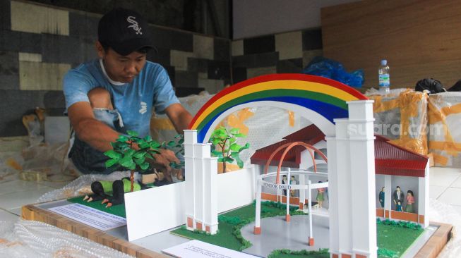 Perajin menyelesaikan pembuatan maket di Maket Diorama, Depok, Jawa Barat, Rabu (26/1/2022).  [Suara.com/Septian]
