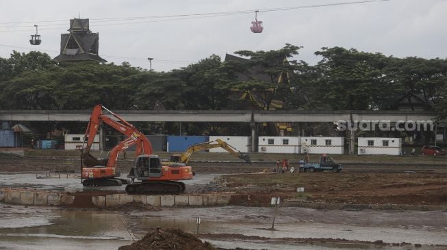 Pekerja dibantu alat berat melakukan pengerukan di danau Taman Mini Indonesia Indah (TMII), Jakarta, Rabu (26/1/2022). [Suara.com/Angga Budhiyanto]