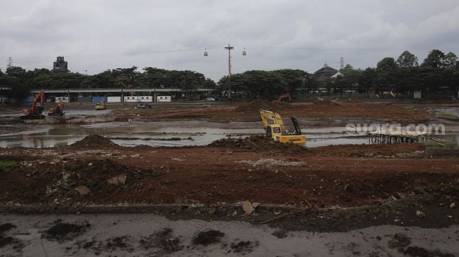 Pekerja dibantu alat berat melakukan pengerukan di danau Taman Mini Indonesia Indah (TMII), Jakarta, Rabu (26/1/2022). [Suara.com/Angga Budhiyanto]