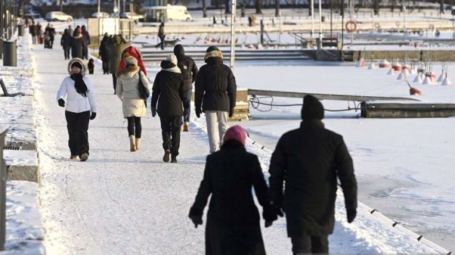 Warga berjalan di tepi laut di hari yang cerah tapi membekukan pada Boxing Day di Helsinki, Finlandia, Minggu (26/12/2021). ANTARA FOTO/Lehtikuva/Heikki Saukkomaa via REUTERS/AWW/djo