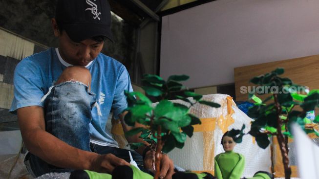 
Perajin menyelesaikan pembuatan maket di Maket Diorama, Depok, Jawa Barat, Rabu (26/1/2022).  [Suara.com/Septian]
