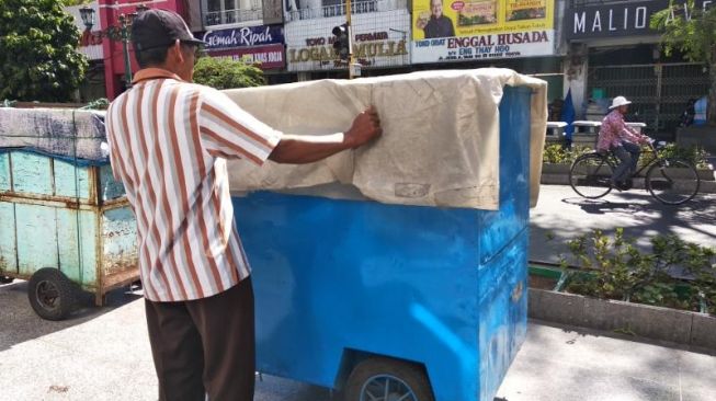 Sejumlah orang tengah mendorong gerobak untuk ditata di tempat berjualan PKL di Malioboro, Kota Jogja, Kamis (27/1/2022). [Muhammad Ilham Baktora / SuaraJogja.id]