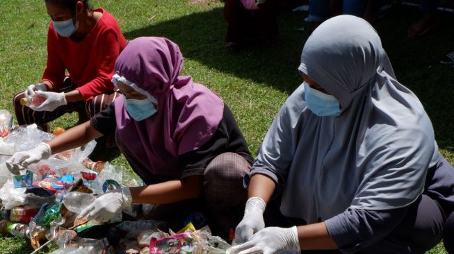 Semangat para warga dalam memilah sampah plastik yang akan diolah kembali [Astra International Tbk].