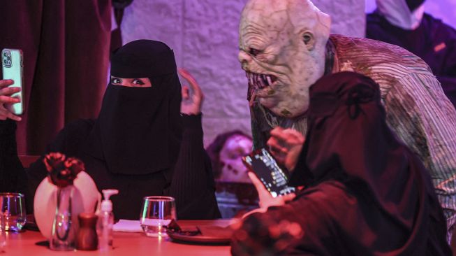 Aktor berkostum zombie memeriahkan suasana di restoran "Shadows" bertema horor di kota hiburan Boulevard, Riyadh, Arab Saudi, pada (19/1/2022). [FAYEZ NURELDINE / AFP]