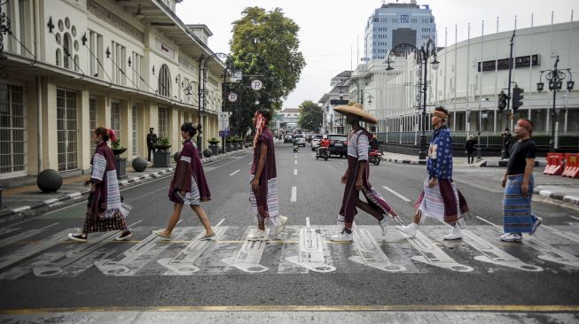 Sejumlah model memeragakan busana dari kain khas nusantara saat penampilan fesyen di ruang publik di Jalan Asia Afrika, Bandung, Jawa Barat, Jumat (28/1/2022). [ANTARA FOTO/Raisan Al Farisi]