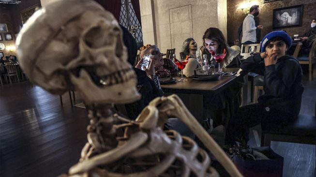 Instalasi kerangka manusia duduk di seberang meja pengunjung di restoran "Shadows" bertema horor di kota hiburan Boulevard, Riyadh, Arab Saudi, pada (19/1/2022). [FAYEZ NURELDINE / AFP]