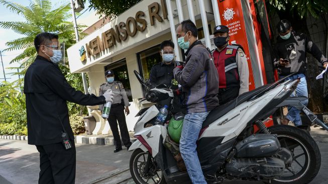 Petugas keamanan menyemprotkan cairan disinfektan pada karyawan di Kantor Pusat Kementerian Sosial (Kemensos), Jakarta, Jumat (28/1/2022). [ANTARA FOTO/M Risyal Hidayat]