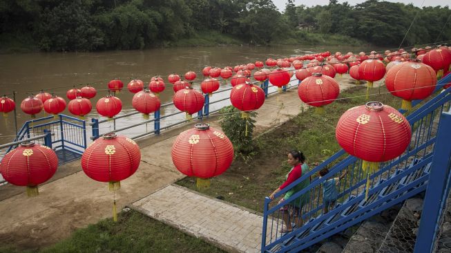 Warga melintas di pinggir Sungai Bengawan Solo yang dihiasi lampion menyambut Tahun Baru Imlek 2022 di Taman Sunan Jogo Kali, Pucang Sawit, Solo, Jawa Tengah, Kamis (27/1/2022). [ANTARA FOTO/Mohammad Ayudha]