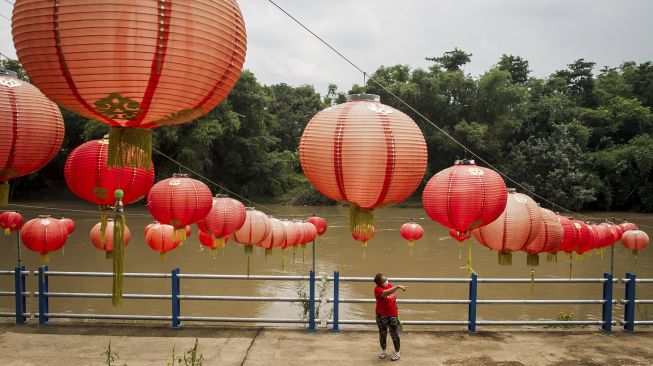 Warga melintas di pinggir Sungai Bengawan Solo yang dihiasi lampion menyambut Tahun Baru Imlek 2022 di Taman Sunan Jogo Kali, Pucang Sawit, Solo, Jawa Tengah, Kamis (27/1/2022). [ANTARA FOTO/Mohammad Ayudha]