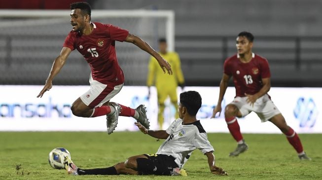 Pemain Timnas Indonesia Ricky Kambuaya (kiri) dihadang oleh pemain Timnas Timor Leste Jhon Frith (bawah) dalam pertandingan sepak bola Leg 1 FIFA Matchday di Stadion I Wayan Dipta, Gianyar Bali, Kamis (27/1/2022). [ANTARA FOTO/Nyoman Budhiana]