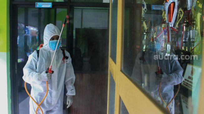 Petugas Palang Merah Indonesia (PMI) menyemprotkan cairan disinfektan di SMA Negeri 66 Jakarta, Jumat (28/1/2022). [Suara.com/Septian]