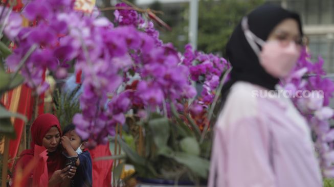 Warga berfoto di depan ornamen dengan nuansa Imlek yang di pasang di sekitar Bundaran Hotel Indonesia (HI), Jakarta, Sabtu (29/1/2022). [Suara.com/Angga Budhiyanto]