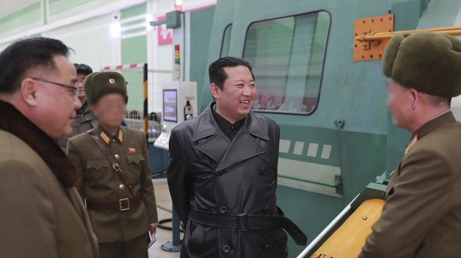 Pemimpin Korea Utara Kim Jong Un (tengah) memeriksa pabrik amunisi yang memproduksi sistem senjata utama di lokasi yang dirahasiakan, dirilis oleh Kantor Berita Pusat Korea (KCNA) Resmi Korea Utara pada (28/1/2022). [STR / AFP / KCNA VIA KNS]