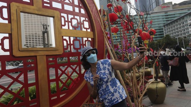 Warga berswafoto di dekat ornamen dengan nuansa Imlek yang di pasang di sekitar Bundaran Hotel Indonesia (HI), Jakarta, Sabtu (29/1/2022). [Suara.com/Angga Budhiyanto]