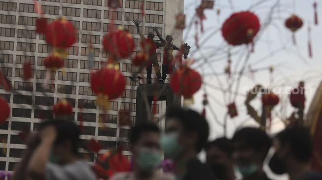 Warga berjalan di dekat ornamen dengan nuansa Imlek yang di pasang di sekitar Bundaran Hotel Indonesia (HI), Jakarta, Sabtu (29/1/2022). [Suara.com/Angga Budhiyanto]