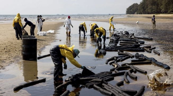 Pekerja membersihkan tumpahan minyak mentah di Pantai Mae Ram Phueng, menyusul tumpahan yang disebabkan oleh kebocoran pipa bawah laut milik Star Petroleum Refining Public Company Limited (SPRC) di Rayong, Thailand, Sabtu (29/1/2022). [JACK TAYLOR / AFP]