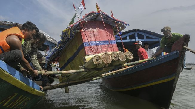 Sejumlah nelayan dan warga melarung (menghanyutkan) sesaji di laut Tarumajaya, Kabupaten Bekasi, Jawa Barat, Jumat (28/1/2022). [ANTARA FOTO/Fakhri Hermansyah]