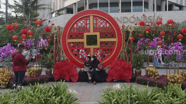 Warga berfoto di depan ornamen dengan nuansa Imlek yang di pasang di sekitar Bundaran Hotel Indonesia (HI), Jakarta, Sabtu (29/1/2022). [Suara.com/Angga Budhiyanto]