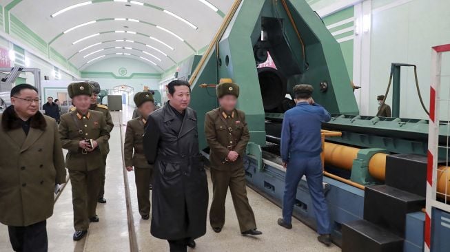 Pemimpin Korea Utara Kim Jong Un (tengah) memeriksa pabrik amunisi yang memproduksi sistem senjata utama di lokasi yang dirahasiakan, dirilis oleh Kantor Berita Pusat Korea (KCNA) Resmi Korea Utara pada (28/1/2022). [STR / AFP / KCNA VIA KNS]