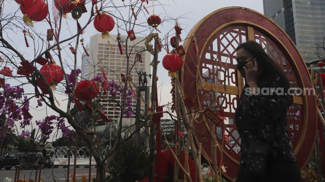 Warga berjalan di dekat ornamen dengan nuansa Imlek yang di pasang di sekitar Bundaran Hotel Indonesia (HI), Jakarta, Sabtu (29/1/2022). [Suara.com/Angga Budhiyanto]