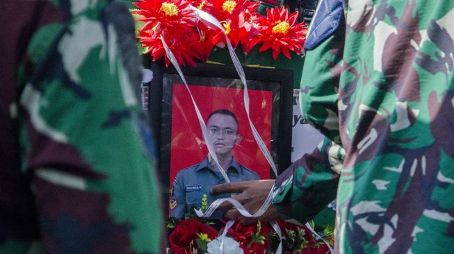 Prajurit TNI memegang foto Prajurit TNI AD Sertu Anumerta Mochamad Rizal Maulana Arifin saat upacara militer pemakaman di Taman Makam Pahlawan Cikutra, Bandung, Jawa Barat, Sabtu (19/1/2022). [ANTARA FOTO/Novrian Arbi]