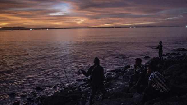 Warga memancing ikan di Pantai Taman Jaya, Pandeglang, Banten, Jumat (28/1/2022). [ANTARA FOTO/Muhammad Adimaja]