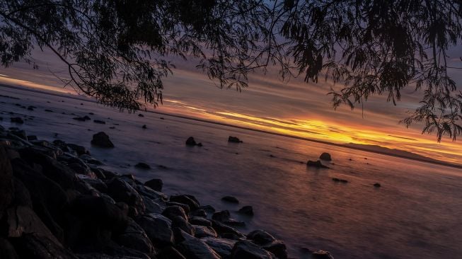 Suasana senja di Pantai Taman Jaya, Pandeglang, Banten, Jumat (28/1/2022). [ANTARA FOTO/Muhammad Adimaja]