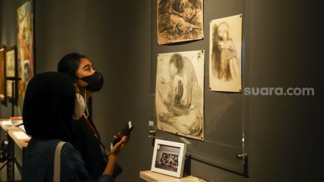 Pengunjung melihat karya seni yang ditampilkan dalam pameran 'Para Sekutu yang Tidak Bisa Berkata Tidak' di Galeri Nasional Indonesia, Jakarta Pusat, Minggu (30/1/2022). [Suara.com/Alfian Winanto]