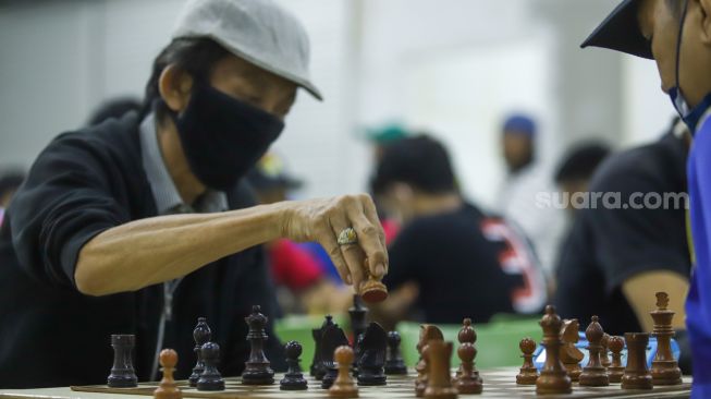 Pecatur mengambil langkah saat bertanding di Kejuaraan Catur Beregu di Tamini Square, Jakarta Timur, Minggu (30/1/2022). [Suara.com/Alfian Winanto]