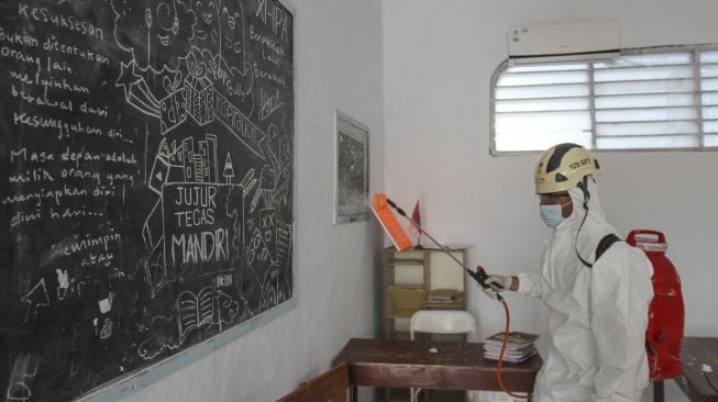 Petugas Palang Merah Indonesia (PMI) menyemprotkan disinfektan di salah satu sekolah di Depok, Jawa Barat, Senin (31/1/2022).  ANTARA FOTO/Asprilla Dwi Adha