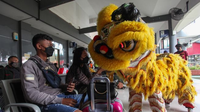 Calon penumpang berinteraksi dengan Barongsai di Stasiun Gubeng Surabaya, Jawa Timur, Senin (31/1/2022).  ANTARA FOTO/Didik Suhartono