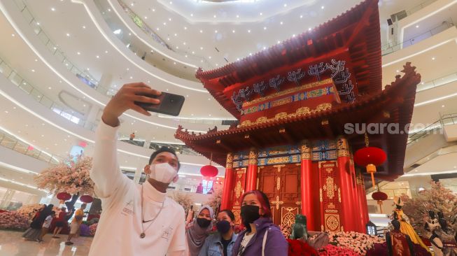 Warga berswafoto dengan latar belakang hiasan Pagoda di salah satu pusat perbelanjaan di Jakarta Pusat, Senin (31/1/2022). [Suara.com/Alfian Winanto]