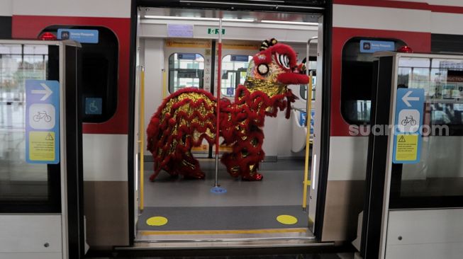 Barongsai menghibur penumpang di dalam gerbong LRT, Jakarta, Selasa (1/2/2022). [Suara.com/Angga Budhiyanto]