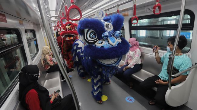 Barongsai menghibur penumpang di dalam gerbong LRT, Jakarta, Selasa (1/2/2022). [Suara.com/Angga Budhiyanto]