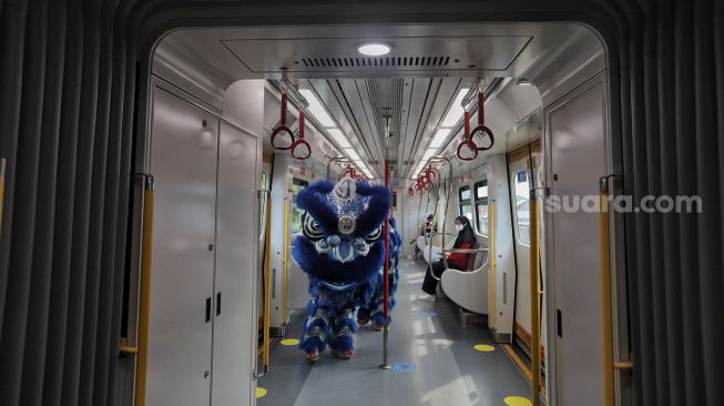 Barongsai menghibur penumpang di dalam gerbong LRT, Jakarta, Selasa (1/2/2022). [Suara.com/Angga Budhiyanto]