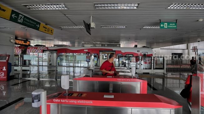 Calon penumpang berjalan memasuki gerbong kereta LRT yang berhenti di Stasiun LRT Velodrome, Pulo Gadung, Jakarta, Selasa (1/2/2022). [Suara.com/Angga Budhiyanto]