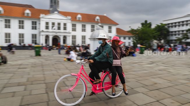 Warga menaiki sepeda hias saat berwisata di Kawasan Kota Tua, Jakarta Barat, Selasa (1/2/2022). [Suara.com/Alfian Winanto]