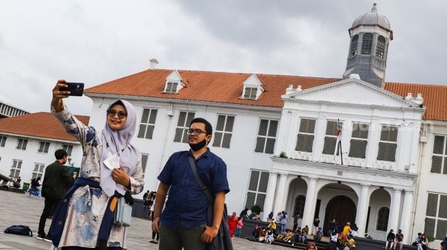 Warga berswafoto saat berwisata di Kawasan Kota Tua, Jakarta Barat, Selasa (1/2/2022). [Suara.com/Alfian Winanto]