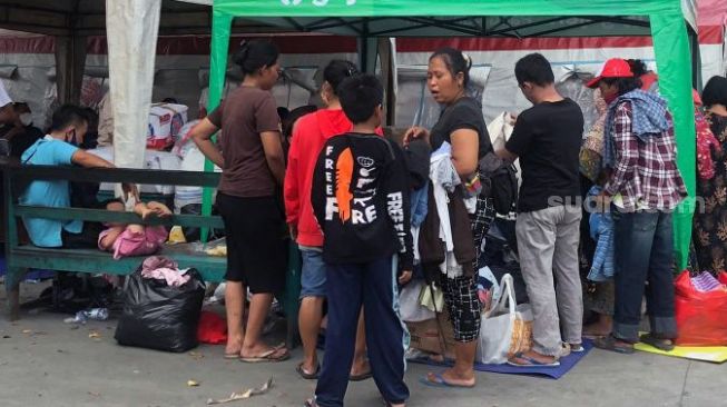 Warga Kebon Jeruk, Jakarta Barat sedang memilah pakaian bekas layak pakai karena sebagian besar warga tidak sempat menyelamatkan harta benda saat kebakaran terjadi, Selasa (1/2/2022). [Suara.com/Faqih Fathurrahman]