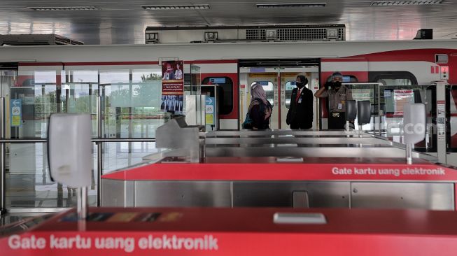 Calon penumpang berjalan memasuki gerbong kereta LRT yang berhenti di Stasiun LRT Velodrome, Pulo Gadung, Jakarta, Selasa (1/2/2022). [Suara.com/Angga Budhiyanto]