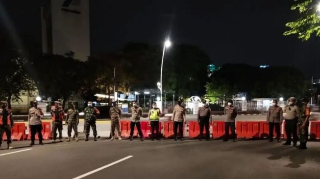 Tangkapan layar aparat kepolisian bersama TNI, dan Satpol PP melaksanakan penutupan jalan antisipasi balap liar di depan gedung Pertamina Jakarta Pusat, Senin (31/1/2022) malam. [Twitter@TMCPoldaMetro]