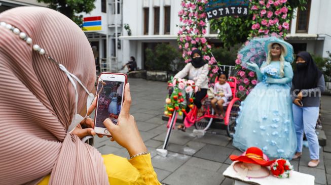 Warga berswafoto saat berwisata di Kawasan Kota Tua, Jakarta Barat, Selasa (1/2/2022). [Suara.com/Alfian Winanto]