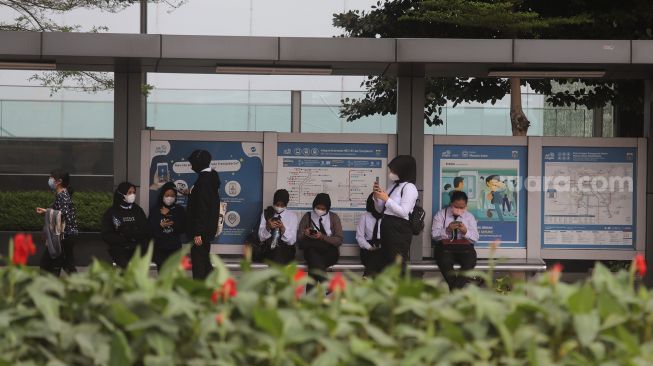 Sejumlah pekerja menunggu bus di kawasan Sudirman, Jakarta, Rabu (2/2/2022). [Suara.com/Angga Budhiyanto]