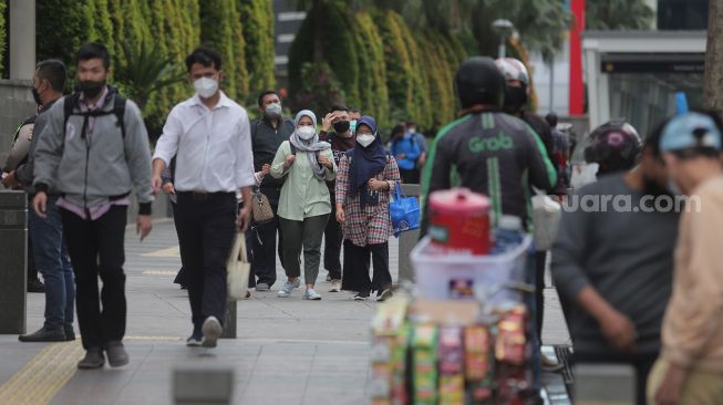 Sejumlah pekerja berjalan di trotoar kawasan Sudirman, Jakarta, Rabu (2/2/2022). [Suara.com/Angga Budhiyanto]