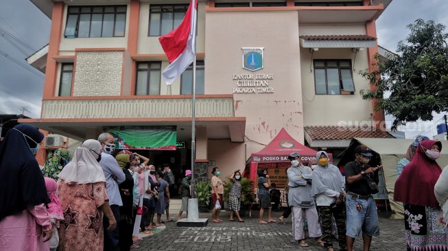 Warga mengantre untuk membeli sembako murah di Kantor Kelurahan Cililitan, Jakarta, Rabu (2/2/2022). [Suara.com/Angga Budhiyanto]