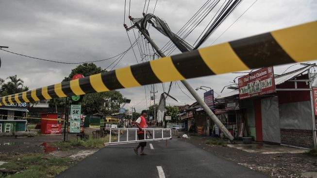 Warga berada di dekat tiang listrik yang roboh di Banguntapan, Bantul, DI Yogyakarta, Rabu (2/2/2022). ANTARA FOTO/Hendra Nurdiyansyah
