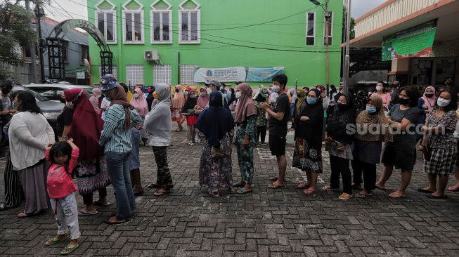 Warga mengantre untuk membeli sembako murah di Kantor Kelurahan Cililitan, Jakarta, Rabu (2/2/2022). [Suara.com/Angga Budhiyanto]